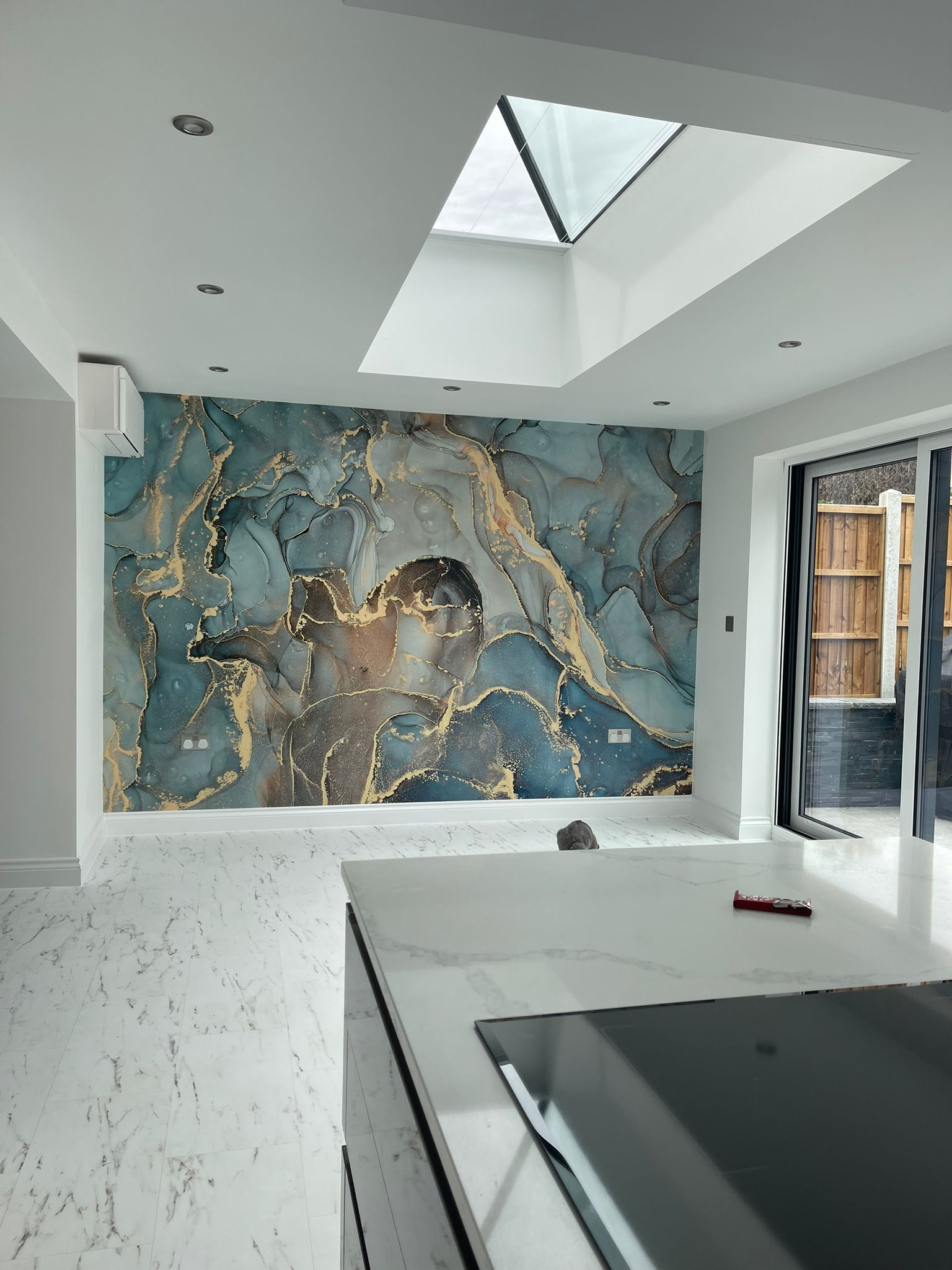 Kitchen with a blue and gold marble effect mural wall under a roof lantern