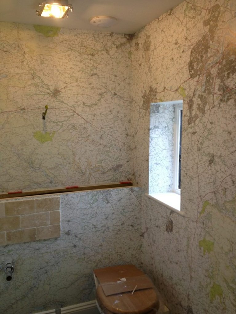 Cloakroom papered in a map print wallpaper