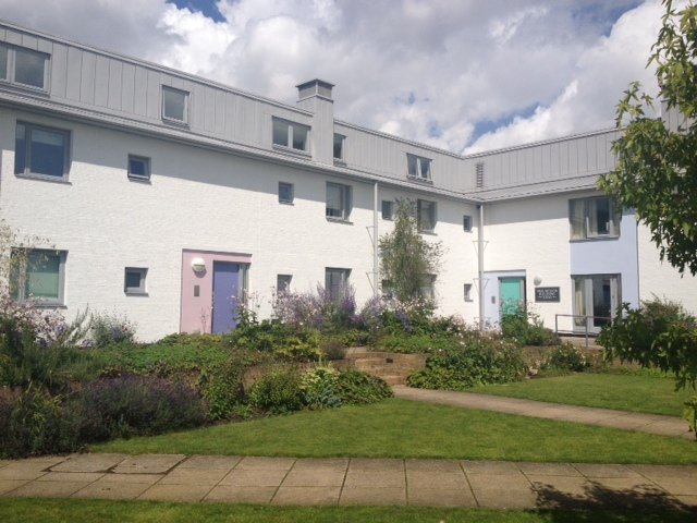 White rendered apartment building with coloured doors