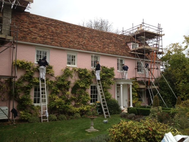 Decorators on ladders painting a pink washed period house