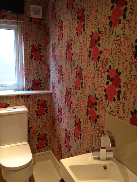 Cloakroom hung with a red floral designer wallpaper
