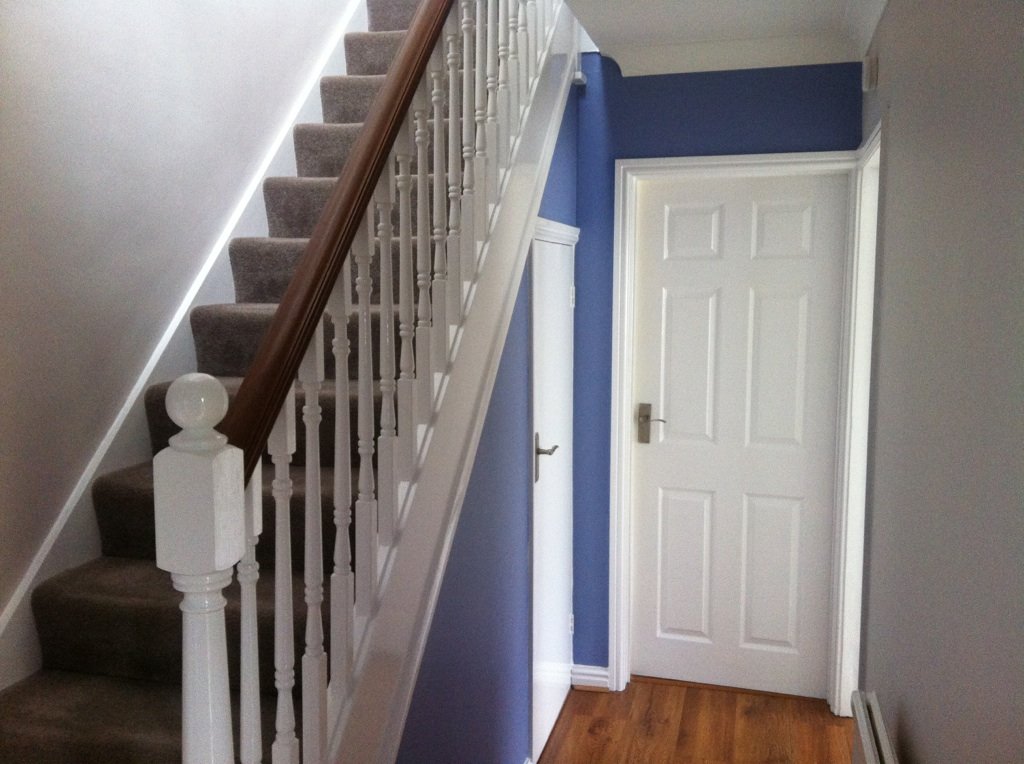 Blue hallway with white spindles and doors