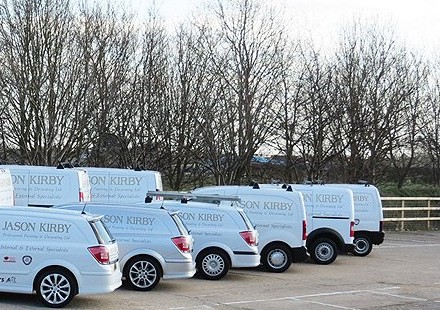 A row of white Jason Kirby company vans